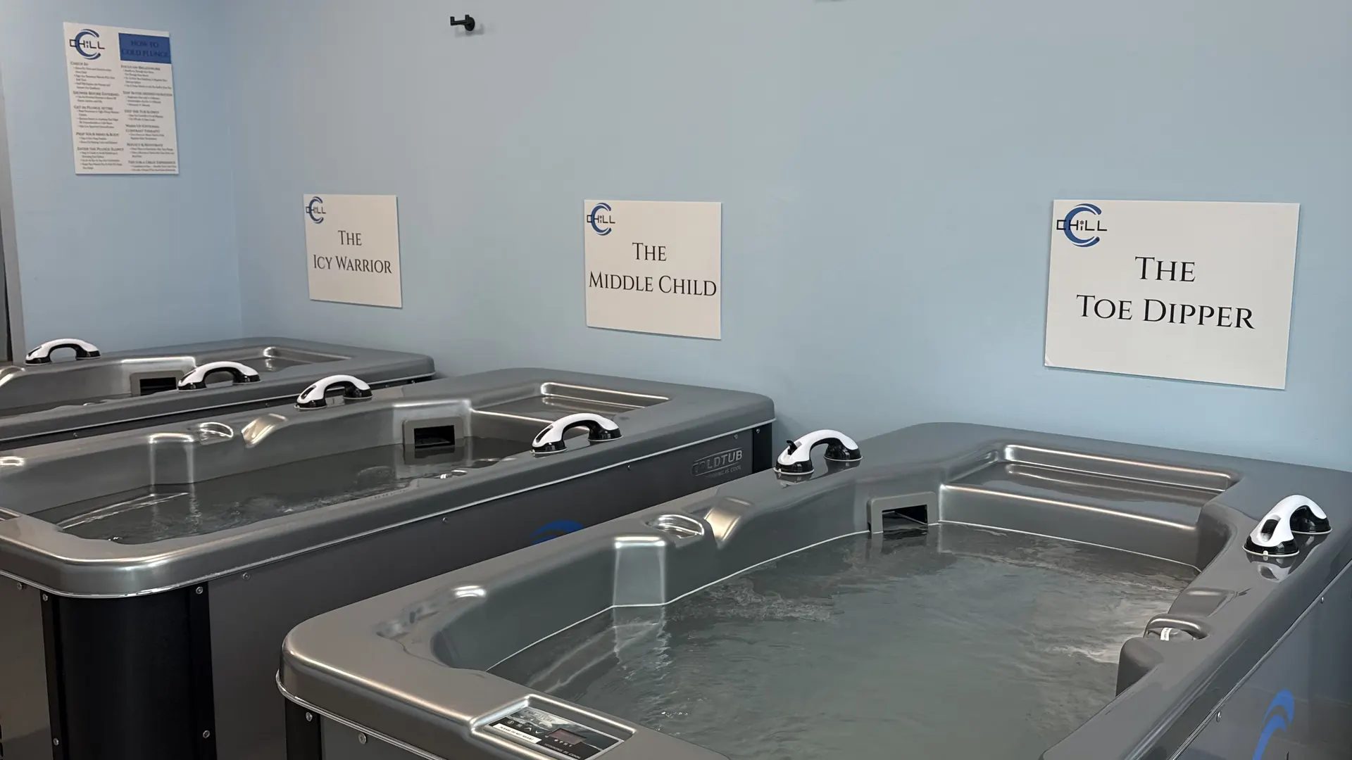 Row of CHILL cold plunge tubs with tub-tier signs on the wall