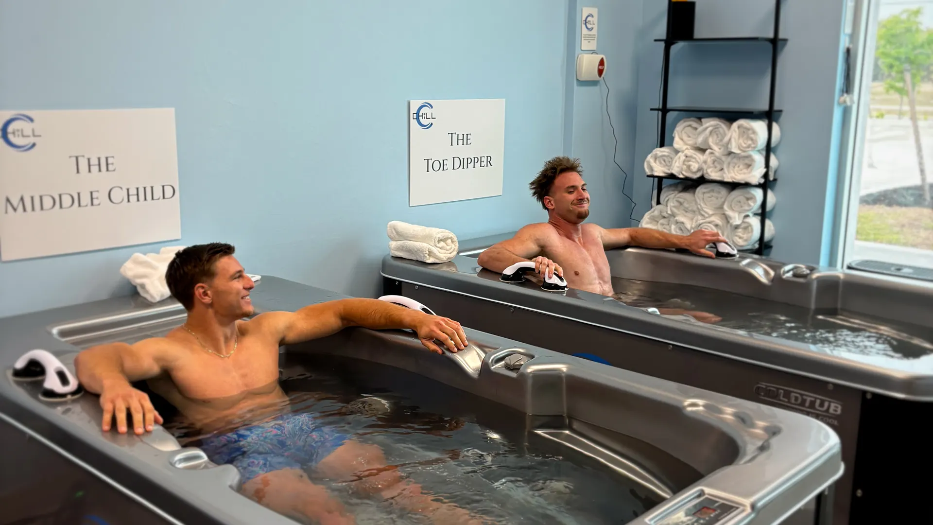 Member relaxing in a CHILL cold plunge tub against the studio’s blue wall