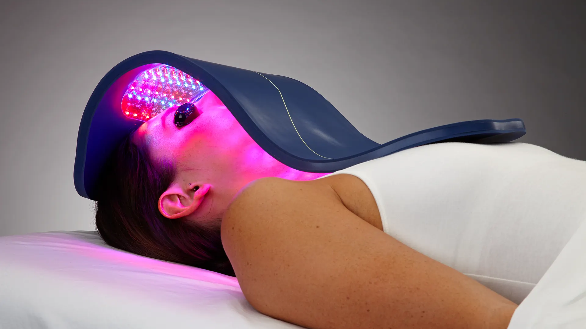 Member receiving a red light therapy session with the Celluma panel curved overhead